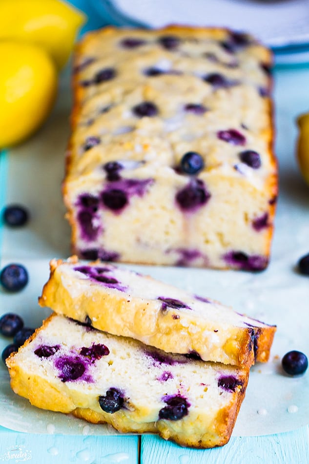 Front view of sliced blueberry bread with lemon and fresh blueberries.