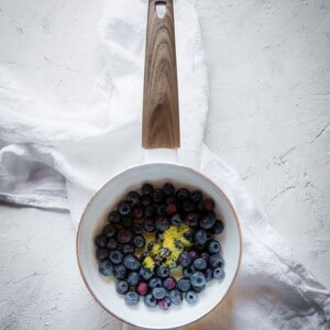 Fresh blueberries, lemon zest and maple syrup in a white pot