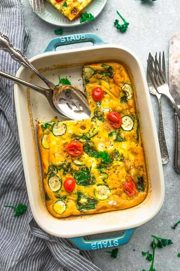 Top view of low carb breakfast egg casserole in a blue casserole pan with a missing slice