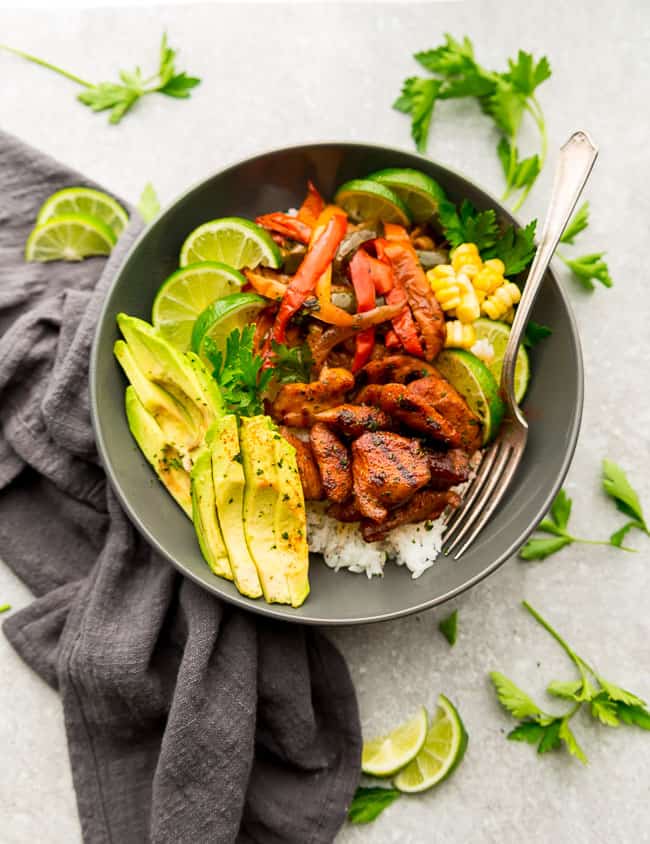 Top view of Chicken Burrito Bowls in a white bowl cilantro lime rice, lime and avocado