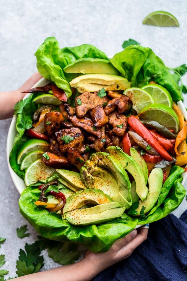 Top view of Whole30 Chicken Burrito Bowls in a white bowl with lettuce, lime and avocado