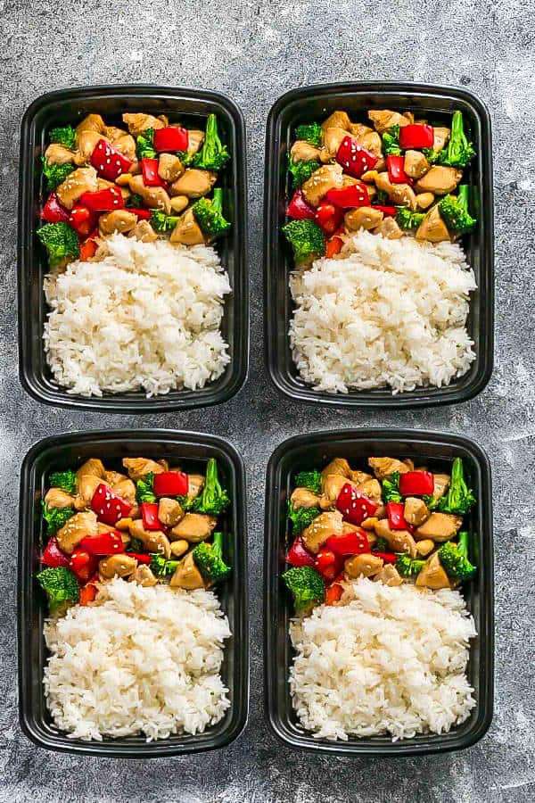 Overhead view of four meal prep containers with rice and Keto Cashew Chicken stir fry