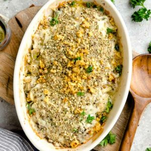 Top view of baked keto cauliflower gratin in a blue oval casserole dish on a wooden board