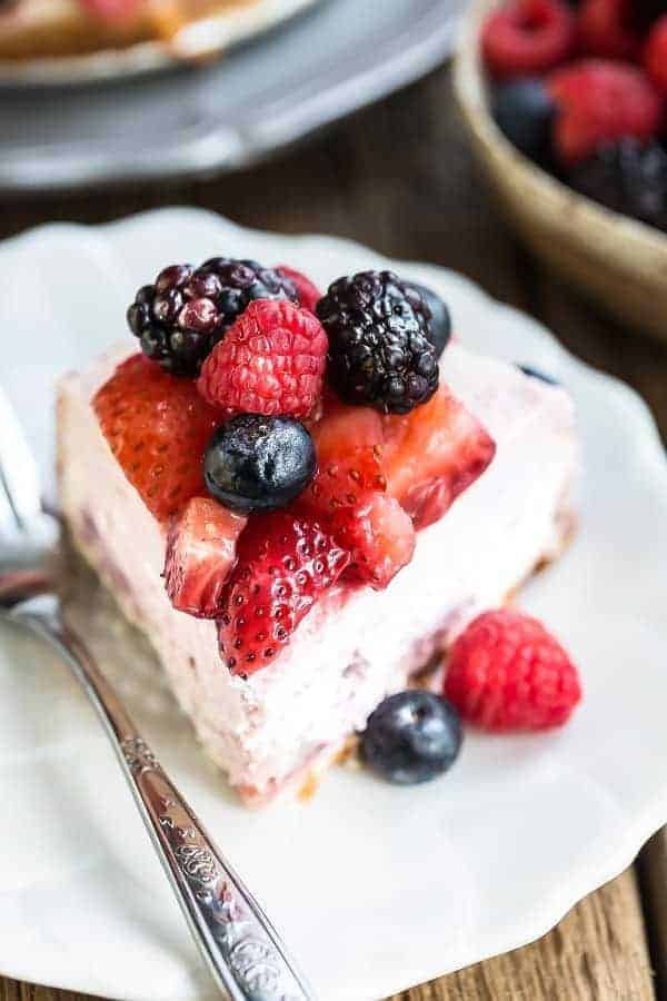 Top view of slice of Keto Cheesecake decorated with mixed berries on a white plate with a fork