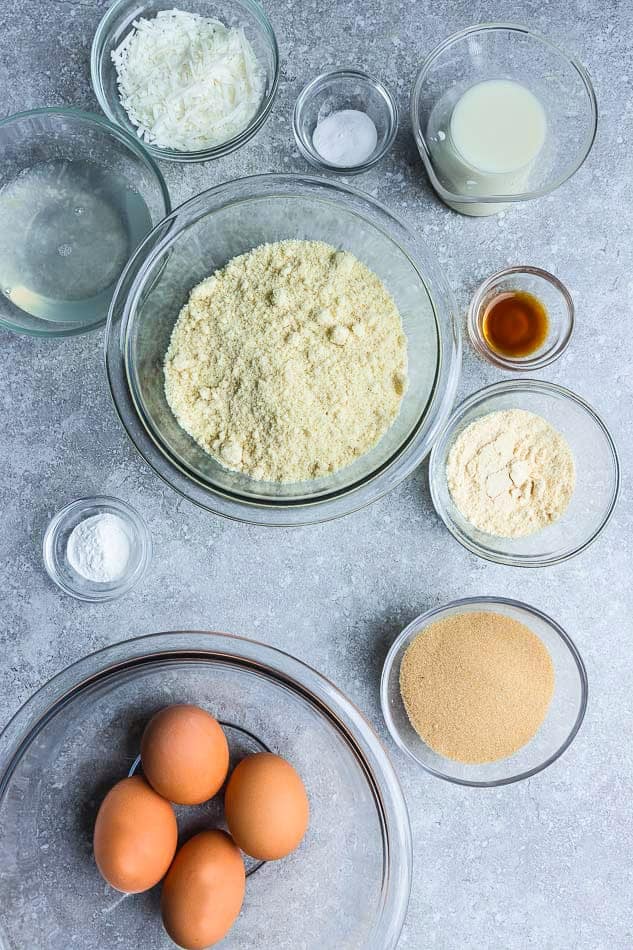 Top view of small bowls of ingredients to make coconut flour pancakes on a grey background