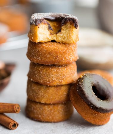 5 Cinnamon Sugar Keto Donuts with chocolate frosting stacked on top of each other on a plate