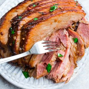 Close up view of cooked instant Pot Ham on a white plate with a fork