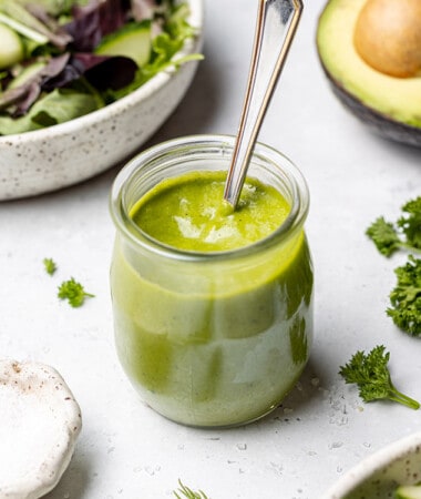45 degree shot of green goddess dressing in a small jar with a spoon