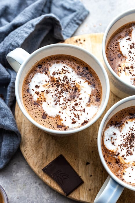Close up top view of the best vegan hot chocolate with vegan whipped cream in three mugs