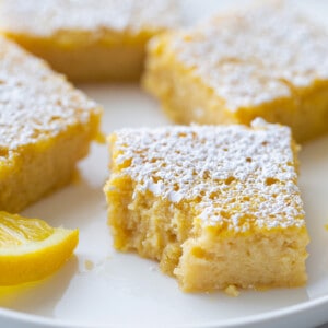 Side view of gluten free lemon bars on a white plate with a missing bite