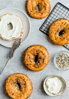 Top view of four Low Carb Keto Bagels with everything bagel seasoning on a grey backgroundwith cream cheese and a knife