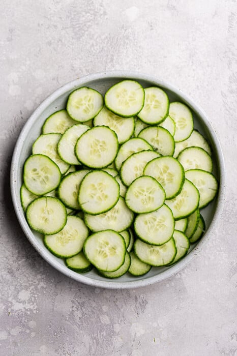 Top view of sliced cucumbers in a white bowl