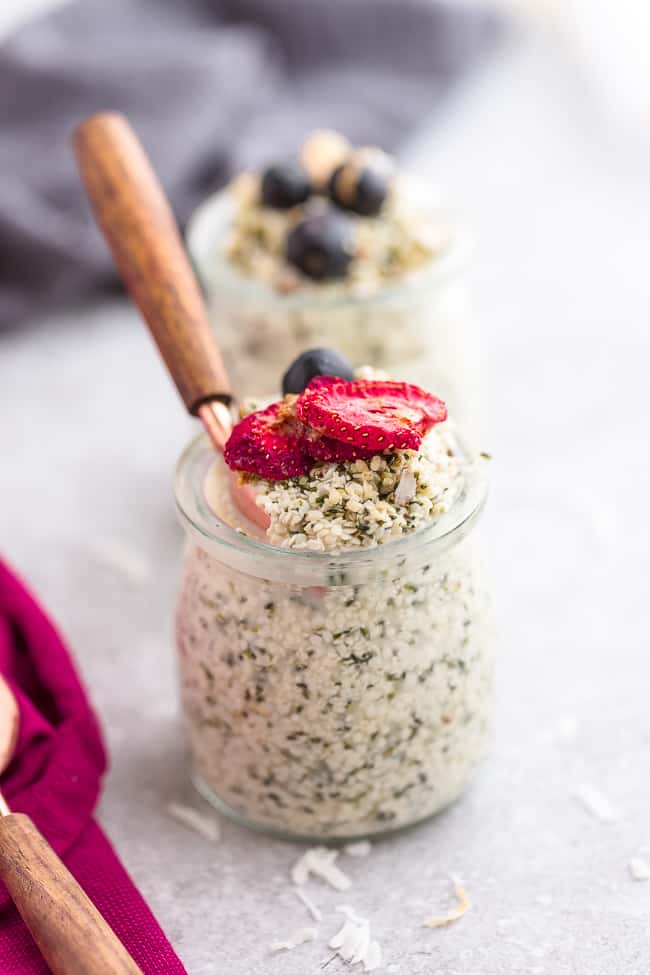 Top view of keto overnight oats in a jar with strawberries, blueberries and raspberries on a grey background