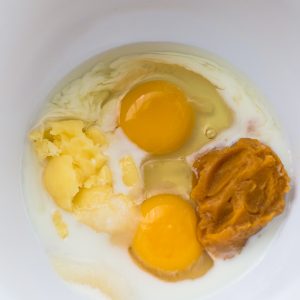 Top view of wet ingredients in a white bowl to make keto pumpkin pie