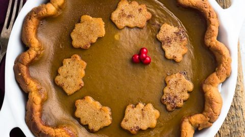 Top view of the best keto pumpkin pie in a white pie plate on a wooden background