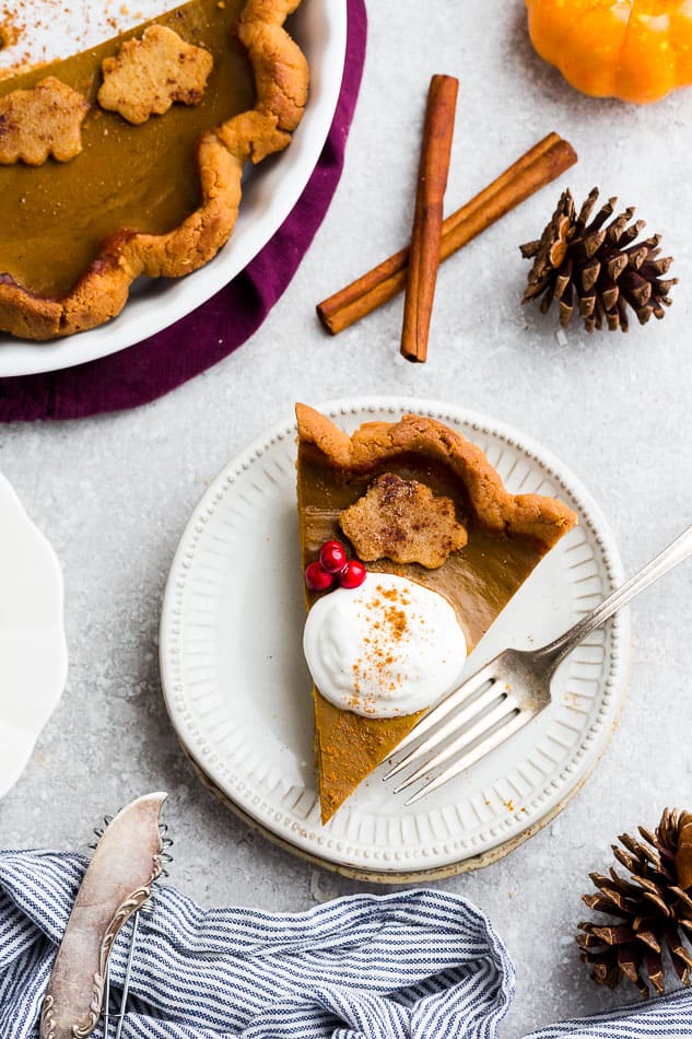 Top view of a slice of keto pumpkin pie with whipped cream on a white plate with whipped coconut cream