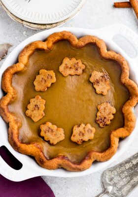 Top view of the best keto pumpkin pie in a white pie plate on a wooden background