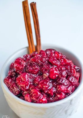 Low carb cranberry sauce in a white bowl with cinnamon sticks