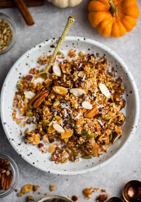 Top view keto pumpkin granola in a white bowl with a gold spoon
