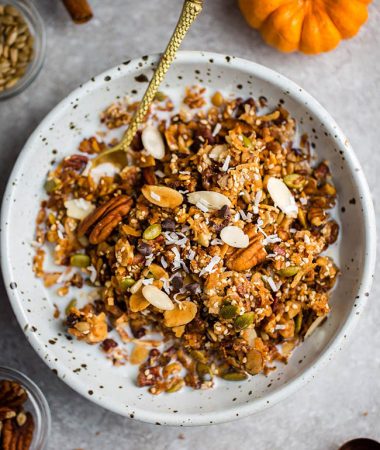 Top view keto pumpkin granola in a white bowl with a gold spoon