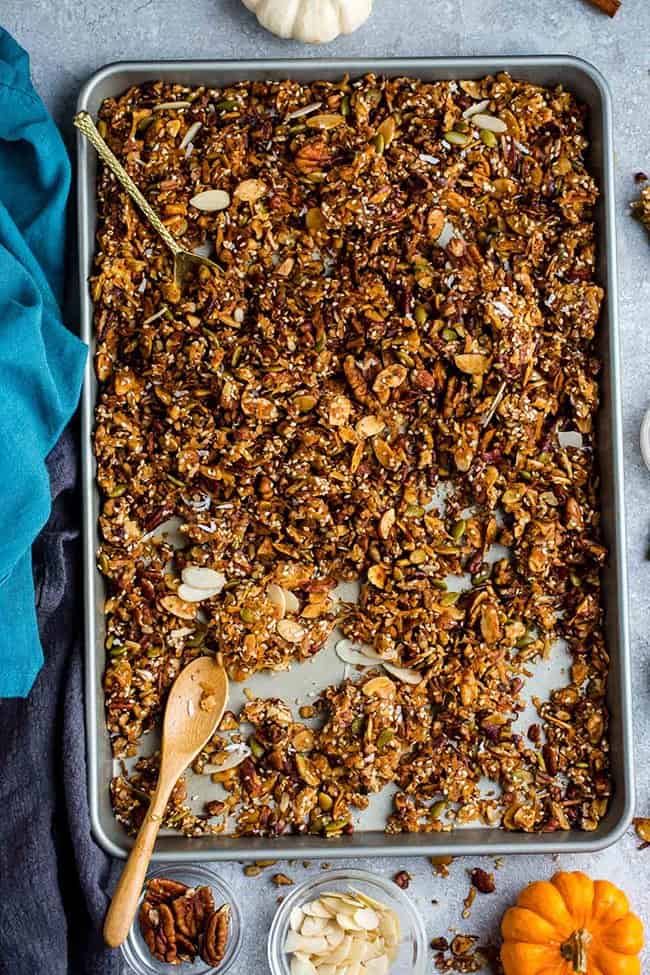 Top view of homemade granola on a baking sheet with a wooden spoon