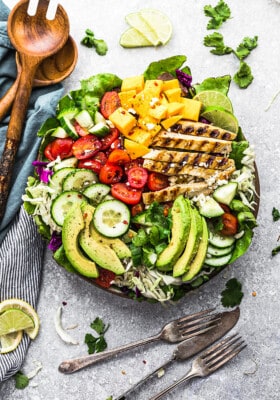 Top view of a loaded grilled mango chicken salad in a bowl with two forks
