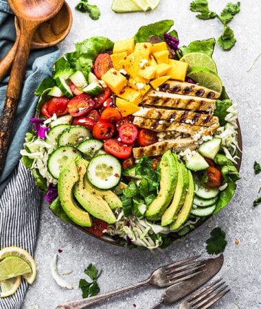 Top view of a loaded grilled mango chicken salad in a bowl with two forks