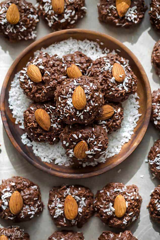 Top view of 6 stacked Low Carb Keto No Bake Cookies in a wooden bowl on a white baking sheet with parchment paper with more cookies