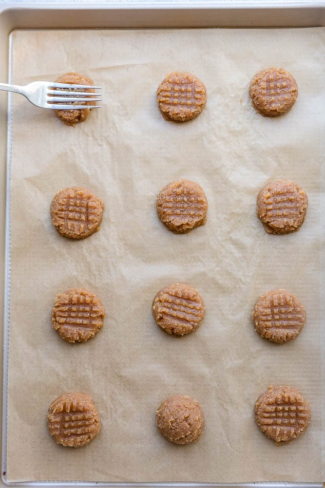 Top view of unbaked keto peanut butter cookies on a baking sheet with a fork