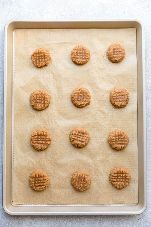 12 unbaked cookies on a metal, parchment-lined baking sheet
