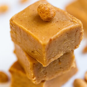 Side view of 3 stacked vegan peanut butter fudge on a white plate