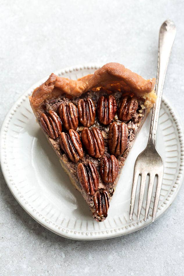 Slice of Keto Pecan Pie on a white plate with a fork