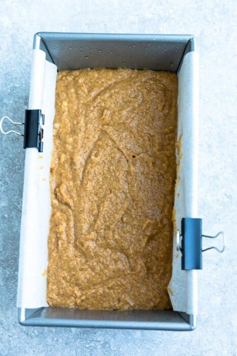 Top view of a 9x5 loaf pan lined with parchment paper with pumpkin bread batter