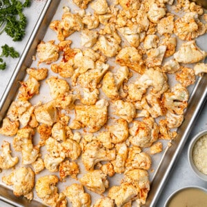 Freshly-baked cauliflower florets on a metal baking sheet lined with parchment paper