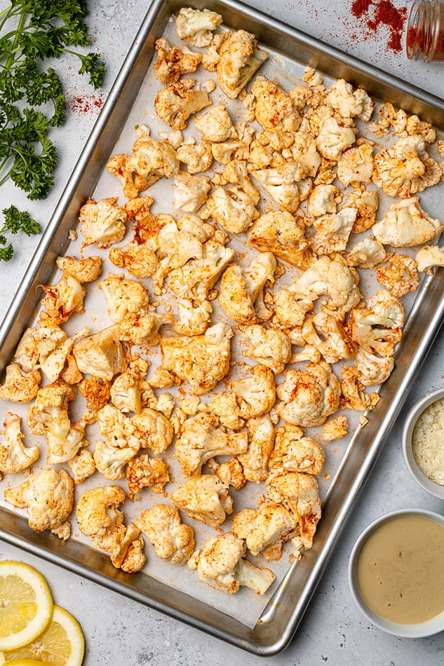 Freshly-baked cauliflower florets on a metal baking sheet lined with parchment paper