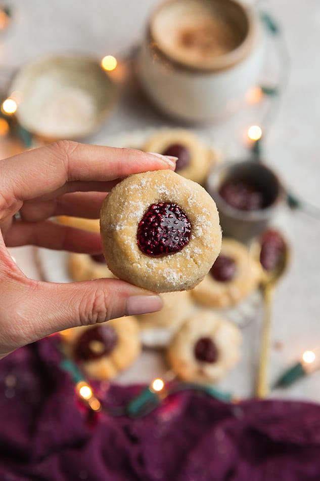 Close up view of a hand holiding one keto thumbprint cookie