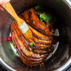 Top view of Instant Pot spiral baked ham in a pressure cooker with a brush