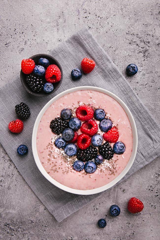 Smoothie bowl on white plate on grey concrete background