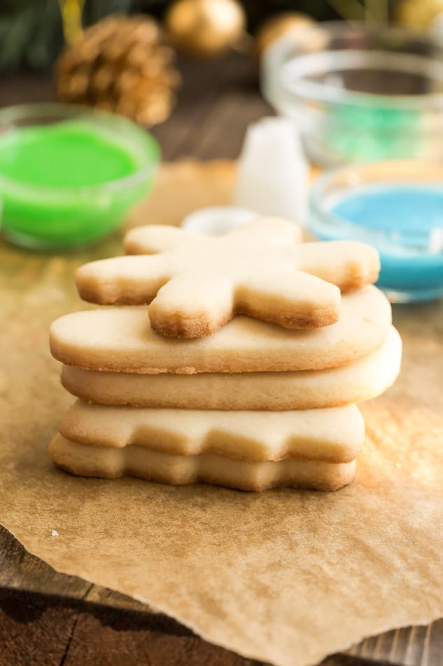 A stack of Keto Sugar cookies next to bowls of colorful icing