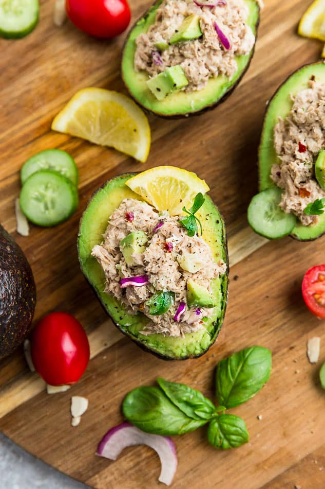 Top view of avocado tuna salad stuffed into 3 avocados on a wooden board