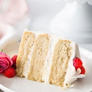 A slice of Keto Vanilla Cake on a white plate garnished with fresh raspberries