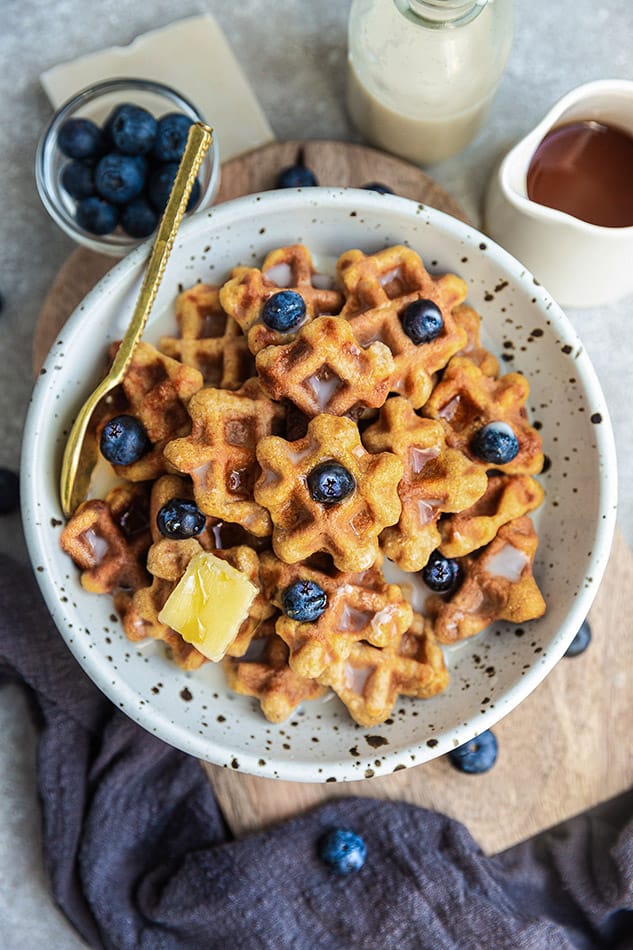 Overhead image of waffle cereal topped with blueberries, butter, and syrup.