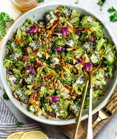 Top view of Keto broccoli salad in a white bowl with gold spoons