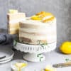 Side view of one low carb lemon cake on a white cake stand with one slice cut out