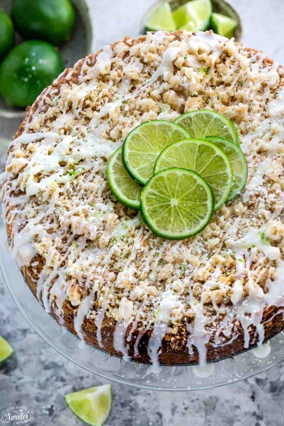 Overhead view of a Key Lime Coffee Cake with streusel topping, white chocolate drizzle, and lime slices for garnish