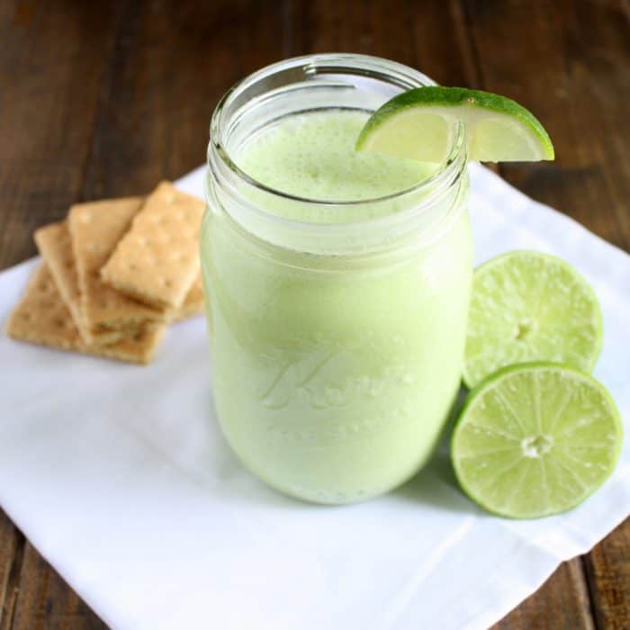 Key Lime Smoothie in a jar with graham crackers and lime halves nearby