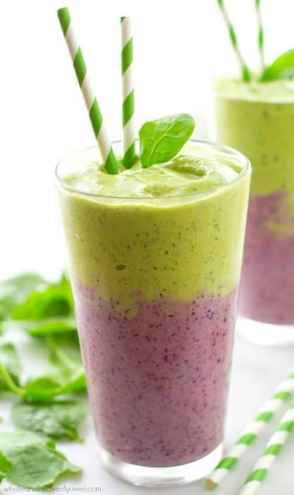 A glass of Layered Mixed Berry Green Smoothie with two straws