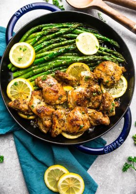 Instant Pot Lemon Butter Chicken on a cast iron skiilet with asparagus and lemon slices