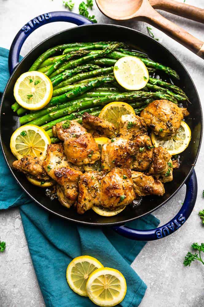 Instant Pot Lemon Butter Chicken on a cast iron skiilet with asparagus and lemon slices