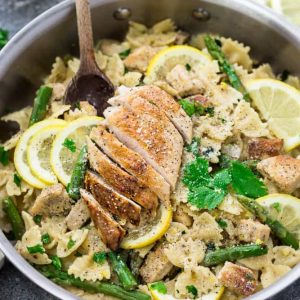 Top view of sautéed chicken strips and gluten-free farfalle pasta in a stainless steel pot